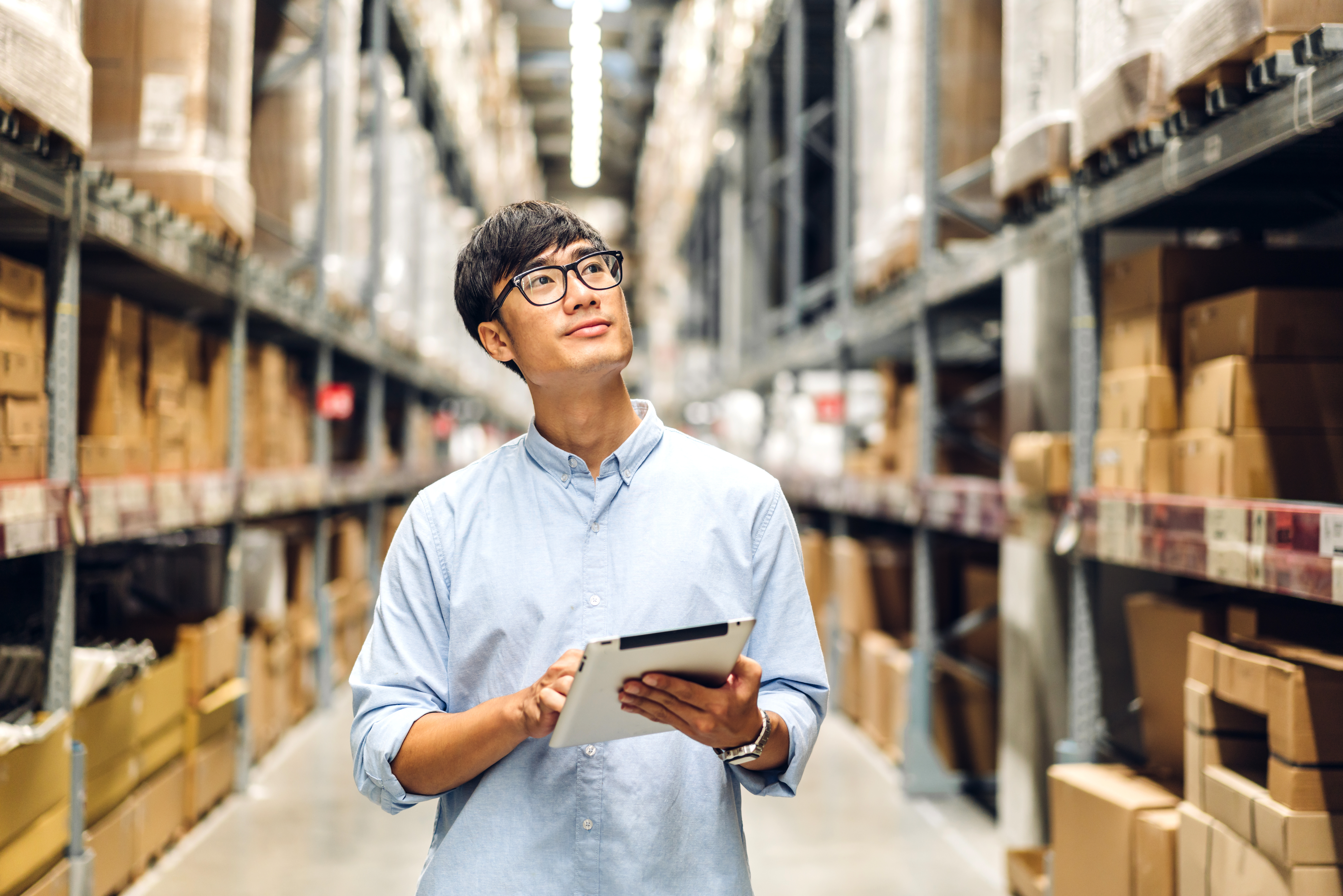 Worker reviewing tagged inventory on a tablet in a warehouse aisle